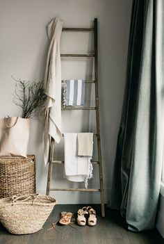 a ladder leaning up against a wall next to a basket with shoes on the floor