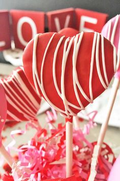 two heart shaped lollipops sitting on top of each other in front of valentine's day decorations