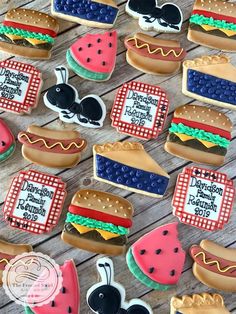 some decorated cookies are sitting on a wooden table and one has a watermelon slice