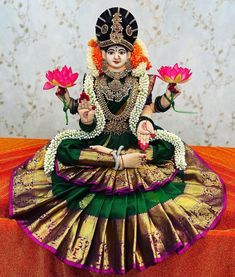 a statue of a woman sitting on top of a table holding two flowers in her hand