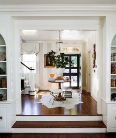 a living room filled with furniture and bookshelves on top of wooden flooring