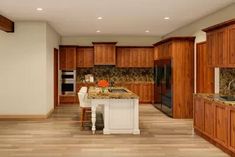 a large kitchen with wooden cabinets and marble counter tops, along with hardwood flooring