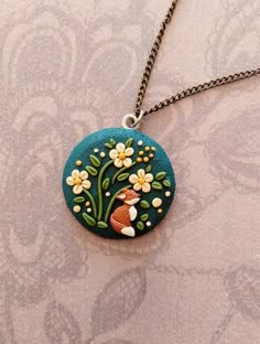 a necklace that has flowers on it and a small bird in the middle with a flowery branch