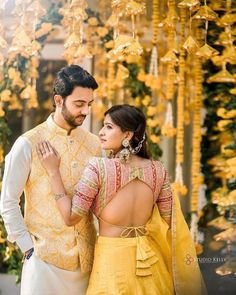 a man and woman standing next to each other in front of some yellow garlands