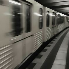 the train is moving fast through the subway station with no people on it's platform