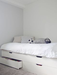 a white bed with drawers underneath it in a room that has carpeted flooring