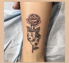 a woman's leg with a rose and two faces tattoo on her left calf