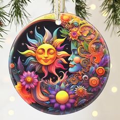 an ornament hanging from a christmas tree decorated with sun and moon designs on it