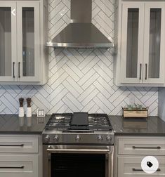 a stove top oven sitting inside of a kitchen next to white cupboards and drawers