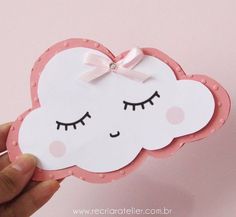 a hand holding up a pink and white cloud shaped card