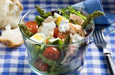 a glass bowl filled with salad next to a piece of bread