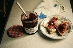 two pieces of pizza on a plate next to a jar of jam