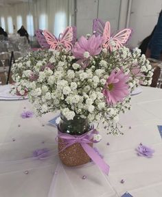 a vase filled with lots of white and pink flowers on top of a table covered in confetti