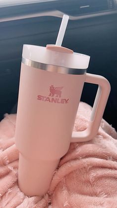 a pink tumbler sitting on top of a blanket in the back of a car