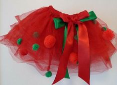 a red tutu with pom - poms on the bottom and green trim