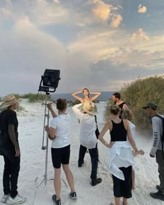 a group of people standing on top of a beach next to a camera set up