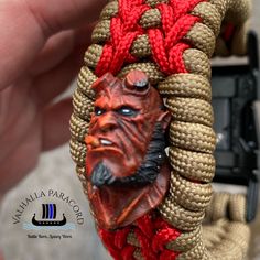 a close up of a person holding a bracelet with a face on it and rope