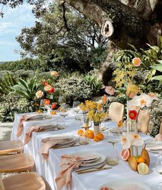 an outdoor table set with plates and flowers