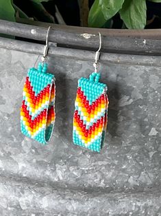 two pairs of colorful beaded earrings hanging from a plant