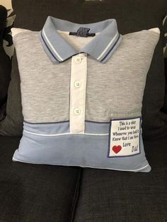 a grey and blue polo shirt pillow on a black couch with a red heart patch