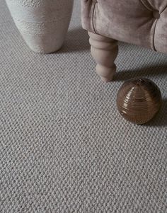 a living room area with a chair, footstool and vase on the floor