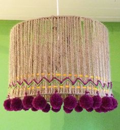 a chandelier hanging from the ceiling with purple pom - poms on it