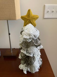 a christmas tree made out of crochet sits on a desk next to a lamp