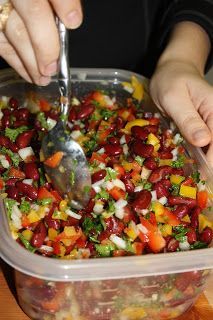 two hands scooping food out of a plastic container with a spoon into the bowl