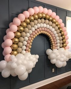 a large arch made out of balloons in the shape of a rainbow on a wall