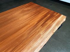 a close up of a wooden table top on concrete flooring with no one around it