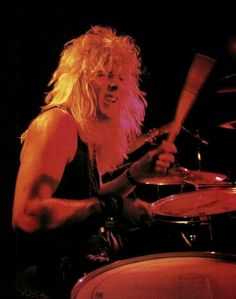 a man with long blonde hair playing drums