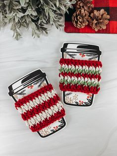 Photo shows 2 crochet coffee cup cozy’s on a paper cup template. Free Crochet Cozy Cup Patterns, Crochet Christmas Cozy Free Pattern, Crochet Mug Sleeve Free Pattern, Christmas Cup Cosy Crochet, Crochet Coffee Cozy Christmas, Cup Warmer Pattern Coffee Sleeve, Crochet Winter Cup Cozy, Christmas Crafts Crochet Easy Diy