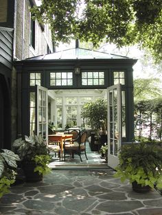 an enclosed patio with table, chairs and potted plants