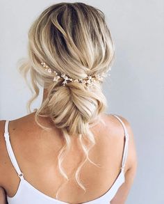 the back of a woman's head wearing a wedding hair piece with pearls in it