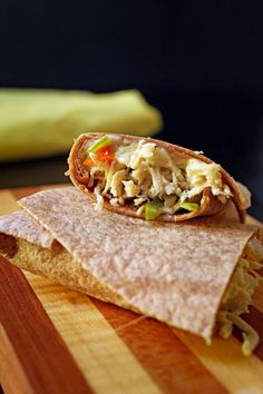 a burrito on a wooden cutting board with a banana in the backround