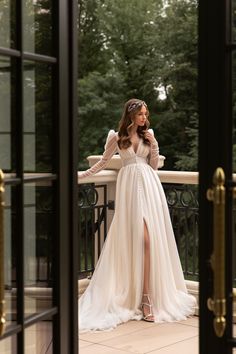 a woman in a white dress standing on a balcony