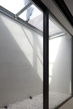 an empty room with glass walls and gravel on the floor