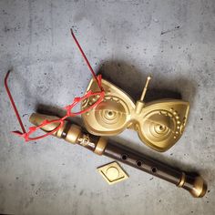 a golden musical instrument with red strings and eye glasses on it's face, sitting on the floor