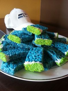 blue and green cake sitting on top of a white plate next to a baseball cap