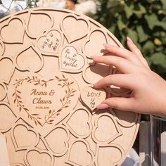 a person holding up a wooden heart shaped plaque with hearts on it's side