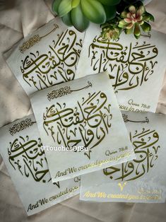 four arabic calligraphys on white paper with green flowers in the middle and gold lettering