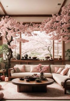 a living room filled with lots of furniture and pink flowers on the trees in bloom