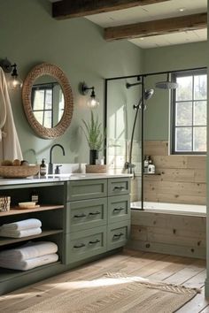 a bathroom with green walls and wooden floors, white towels on the floor and large mirror