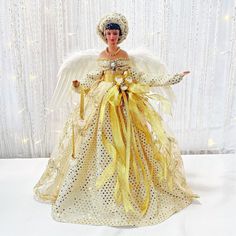 a doll dressed in white and gold with wings