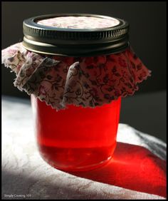 a glass jar filled with red liquid sitting on top of a white cloth covered table