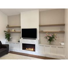 a living room with a couch, fireplace and television on the wall in front of it