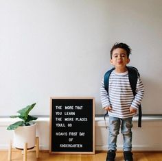 a young boy standing in front of a sign