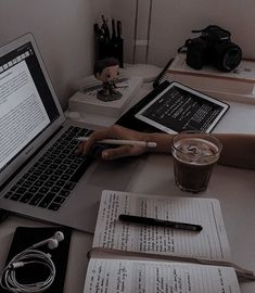 a laptop computer sitting on top of a desk next to a cup of coffee and pen