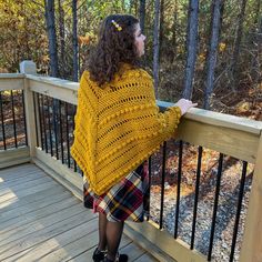 a woman standing on a deck wearing a yellow sweater