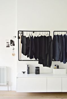 clothes hanging on racks in front of a white wall and radiator next to it